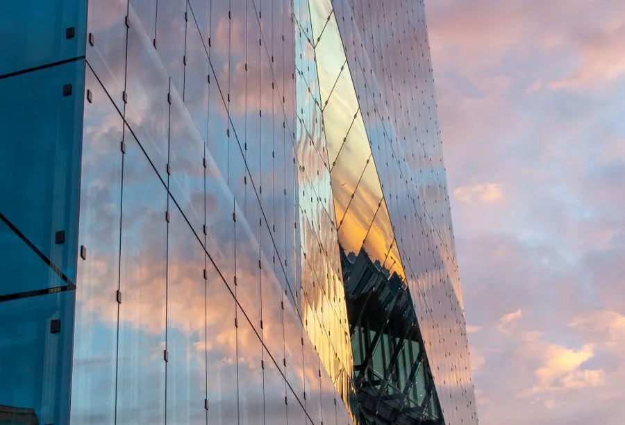 Fachada acristalada de un edificio financiero reflejando el cielo