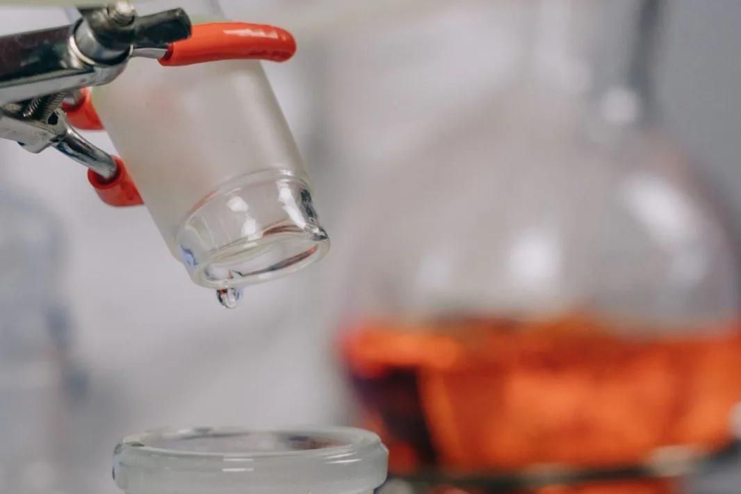 Pipeta vertiendo líquido en un matraz de laboratorio